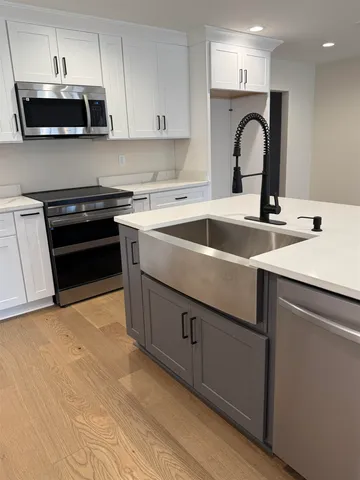 a large kitchen with stainless steel appliances a sink a stove a refrigerator a center island and cabinets