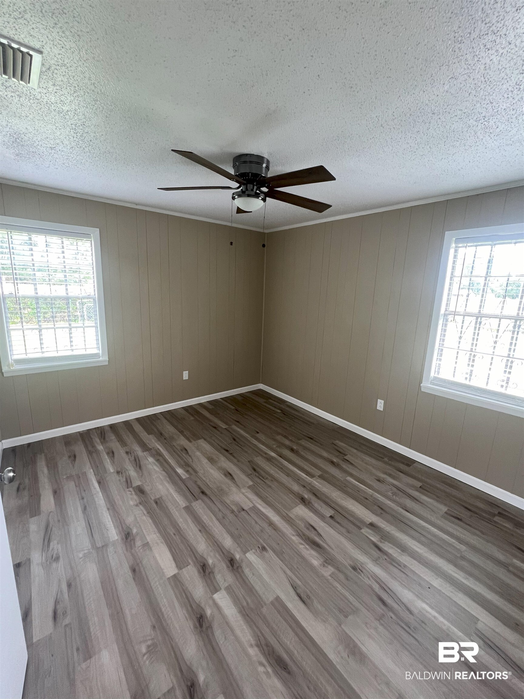 508 Freemanville Drive Atmore, AL 36502 - Photo 19 of 27 Empty room featuring a textured ceiling, wood-type flooring, a healthy amount of sunlight, and ceiling fan