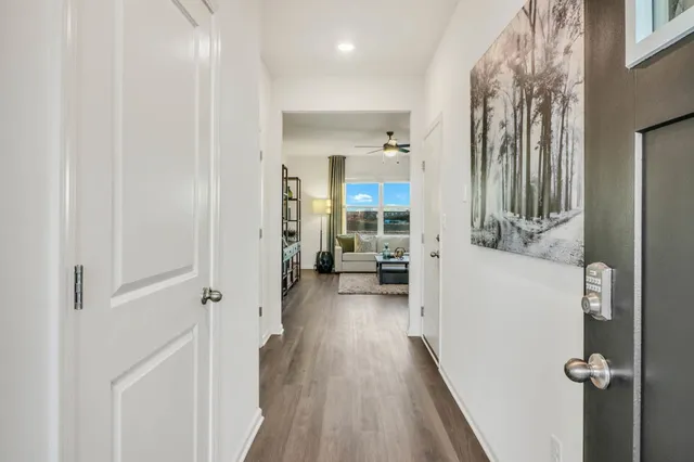 a view of a hallway with wooden floor and living room