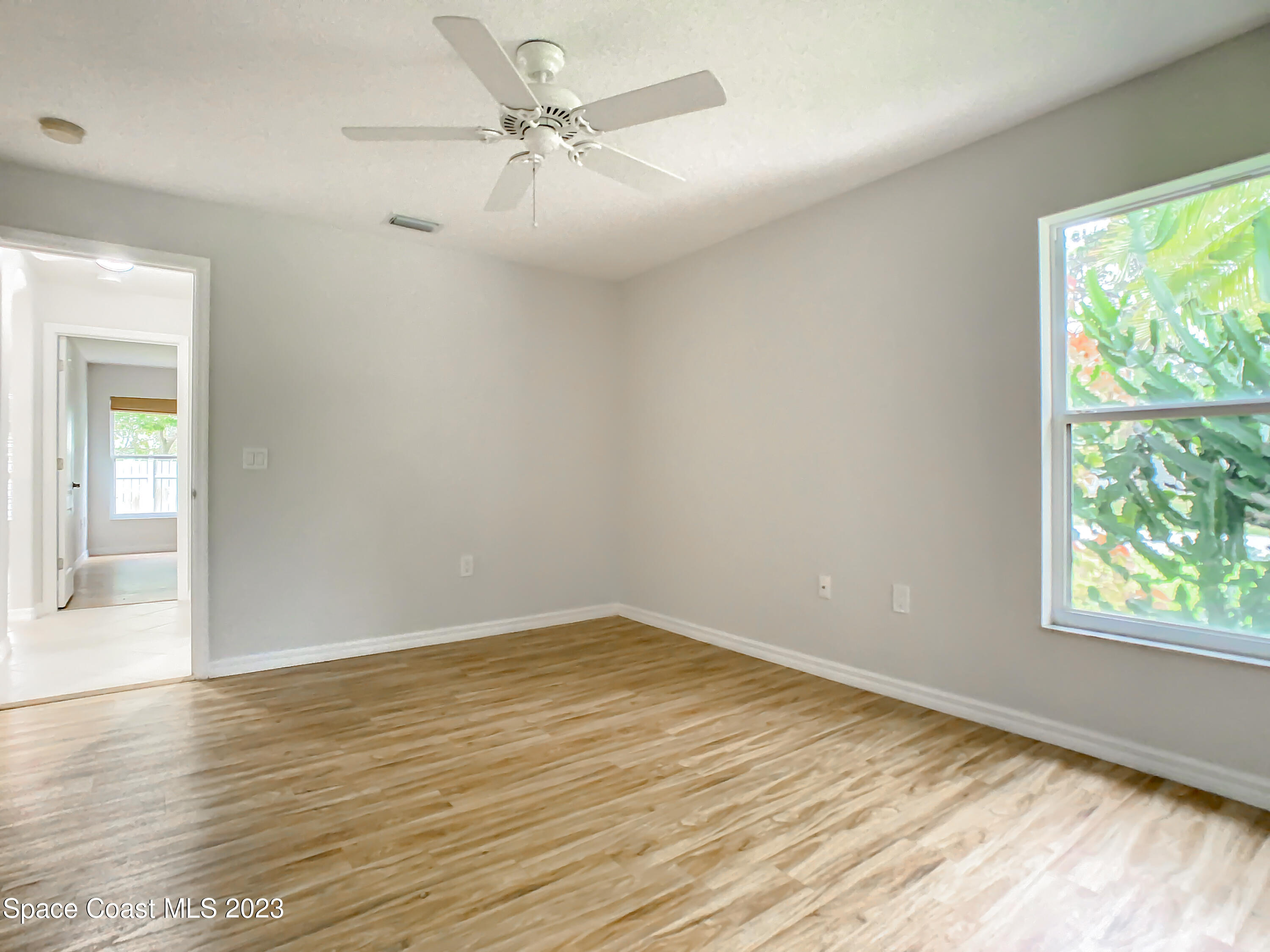 1965 Gates Road Merritt Island, FL 32952 - Photo 25 of 54 an empty room with wooden floor fan and windows
