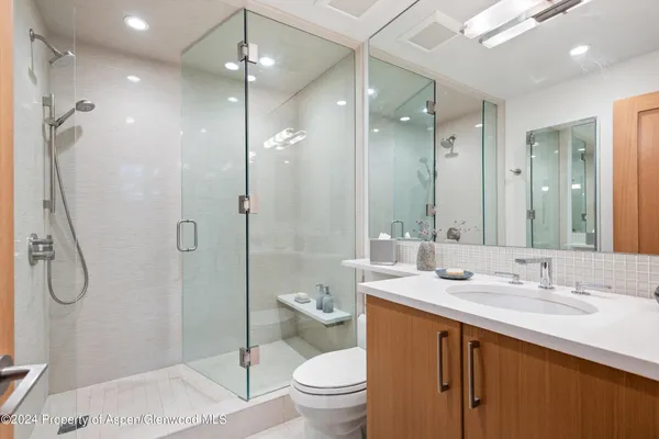 a bathroom with a granite countertop sink a toilet and shower