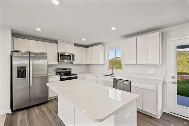 a kitchen with a refrigerator a stove a sink and white cabinets with wooden floor