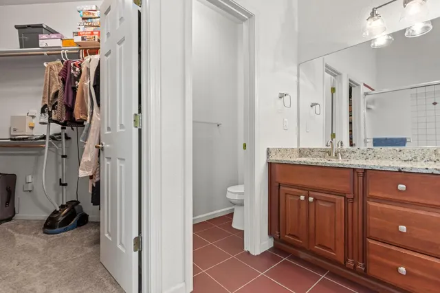 a bathroom with a granite countertop sink a toilet and a mirror