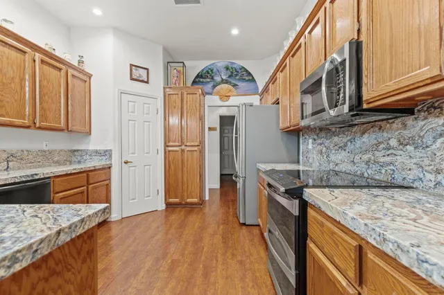 a kitchen with stainless steel appliances granite countertop a refrigerator a stove and a sink dishwasher