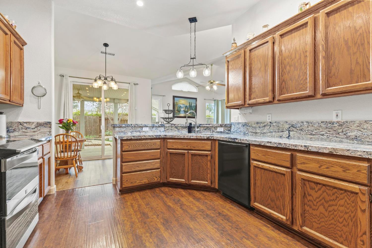 1090 Portola Valley Road Yuba City, CA 95993 - Photo 24 of 42 a kitchen with stainless steel appliances kitchen island granite countertop a stove a sink dishwasher and white cabinets with wooden floor