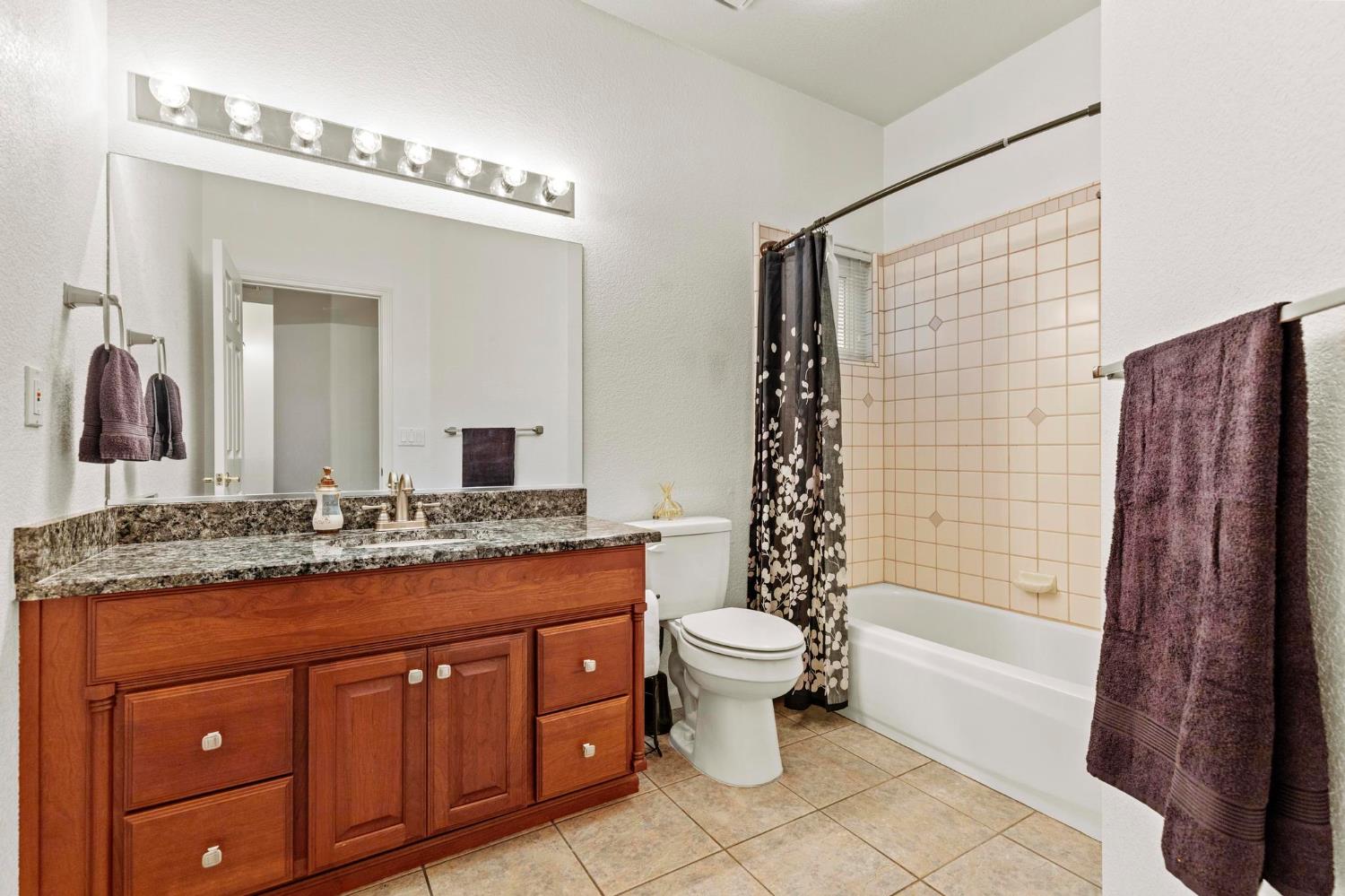 1090 Portola Valley Road Yuba City, CA 95993 - Photo 29 of 42 a bathroom with a granite countertop sink toilet a mirror a vanity and shower