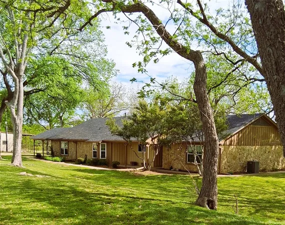 a front view of a house with a garden and trees