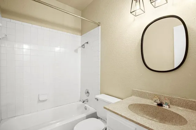 a bathroom with a granite countertop sink a mirror and a bathtub
