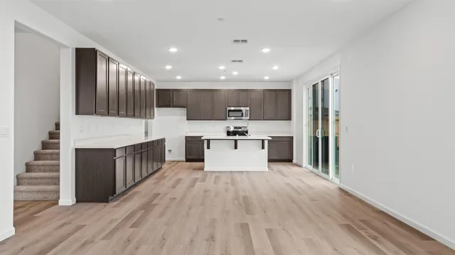 a large kitchen with stainless steel appliances granite countertop a large center island a stove a refrigerator and cabinets