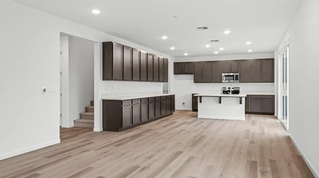 a large kitchen with kitchen island a sink wooden floor and stainless steel appliances