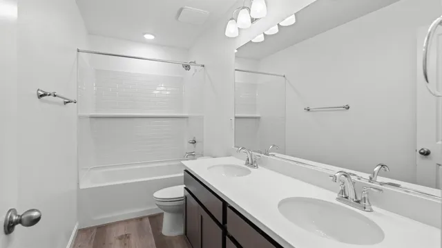 a bathroom with a sink a toilet a mirror and shower