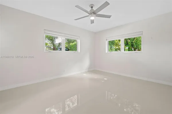 an empty room with windows and fan