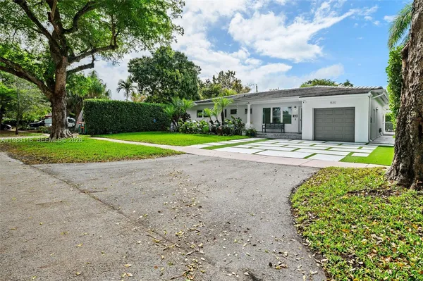 a front view of a house with a yard and trees