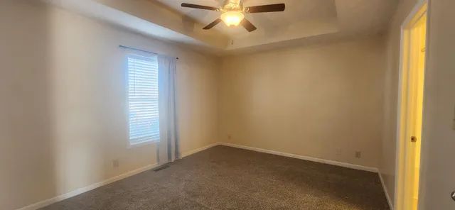 an empty room with a window and a ceiling fan
