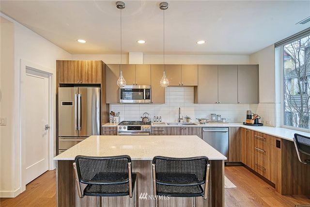 a kitchen with stainless steel appliances granite countertop a dining table chairs refrigerator and microwave
