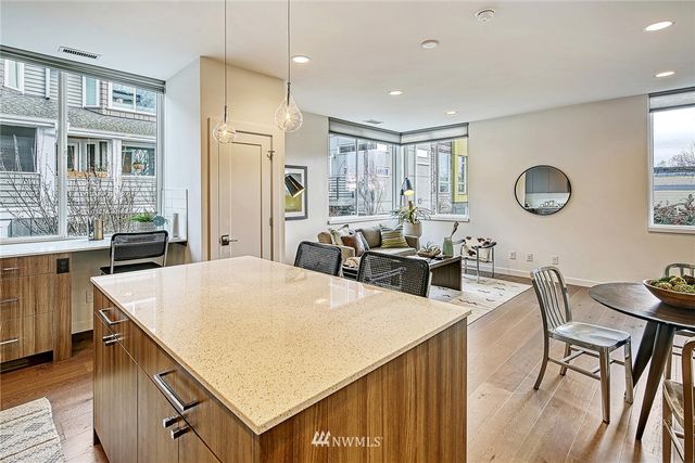 a living room with stainless steel appliances furniture a dining table and kitchen view