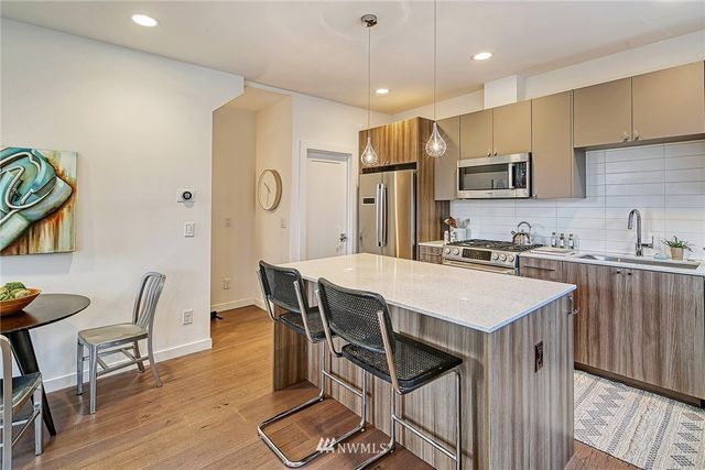a kitchen with stainless steel appliances a kitchen island hardwood floor sink stove dining table and chairs