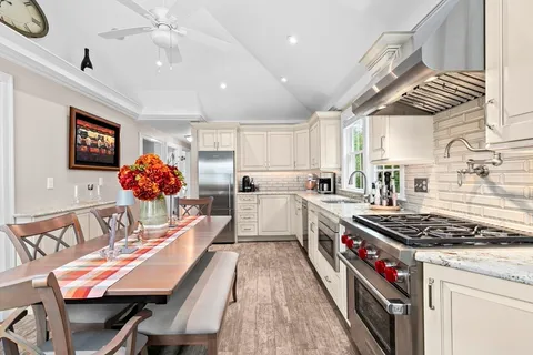 a kitchen with stainless steel appliances granite countertop a stove a sink dishwasher and a dining table with wooden cabinet