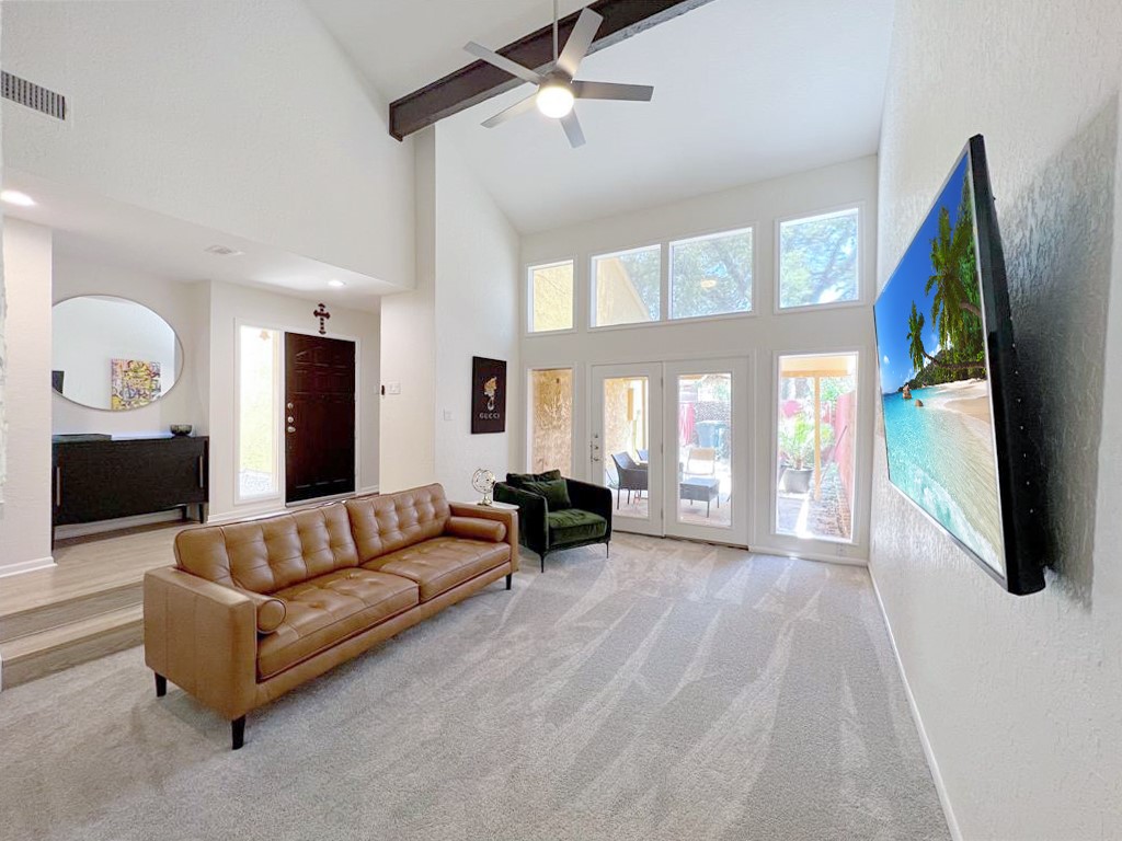 Newly carpeted living area with visible vents, ceiling fan, high vaulted ceiling, beamed ceiling