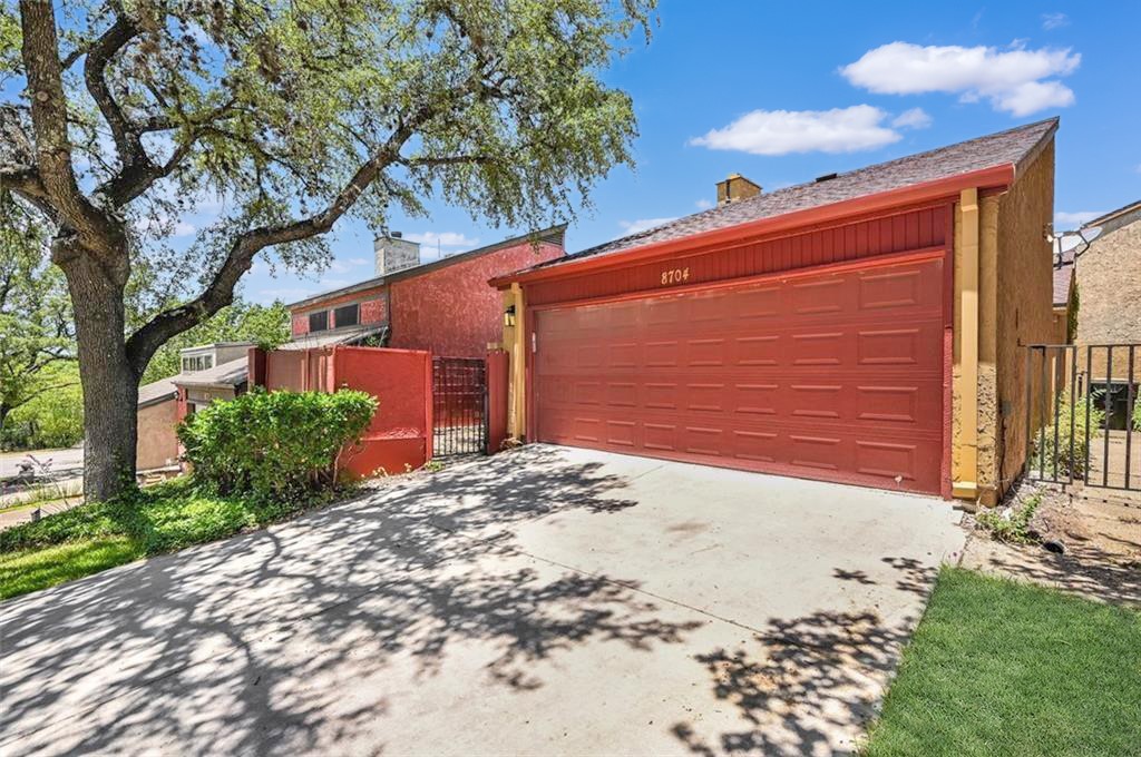 8704 Merion Circle Austin, TX 78754 - Photo 16 of 16 Property exterior featuring a red garage door, concrete driveway, and mature tree