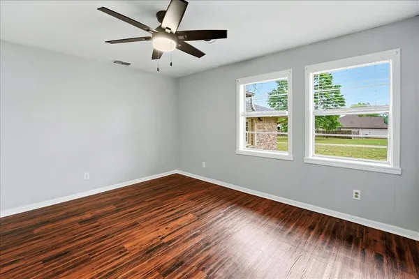 a view of an empty room with wooden floor and a window