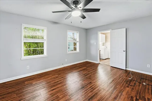 a view of an empty room with wooden floor and a window