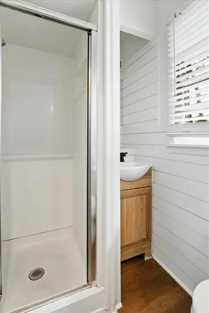 an empty room with wooden floor chandelier fan and windows