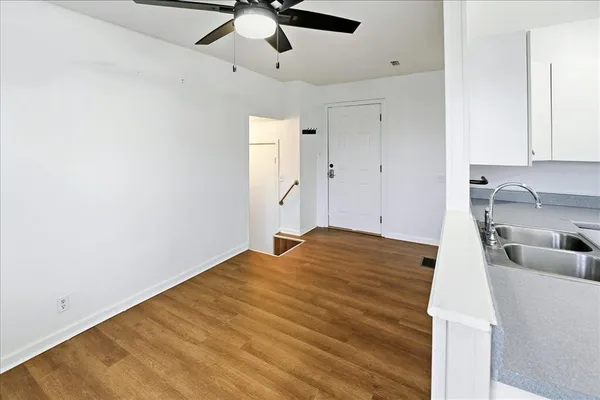 a view of an empty room with wooden floor and a window