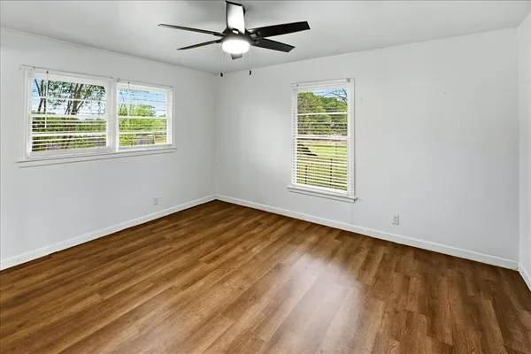 an empty room with wooden floor a ceiling fan and closet