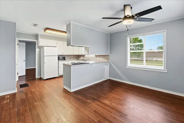a kitchen with stainless steel appliances granite countertop a stove a refrigerator and a microwave oven on the wooden floor
