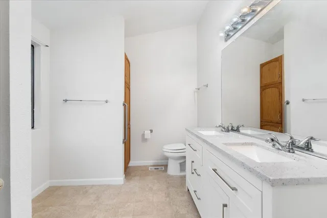 a bathroom with a granite countertop sink mirror vanity and toilet