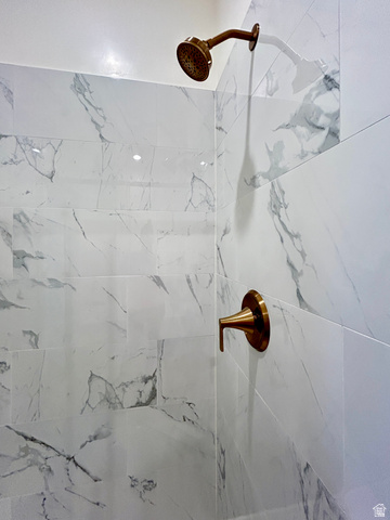 6 South 450th West Gunnison, UT 84634 - Photo 32 of 45 Shower enclosure featuring large format white tiled walls with gray veining, a bronze-finish shower head, and coordinating bronze-finish control handle