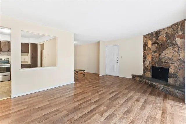 a view of an empty room with wooden floor and a fireplace