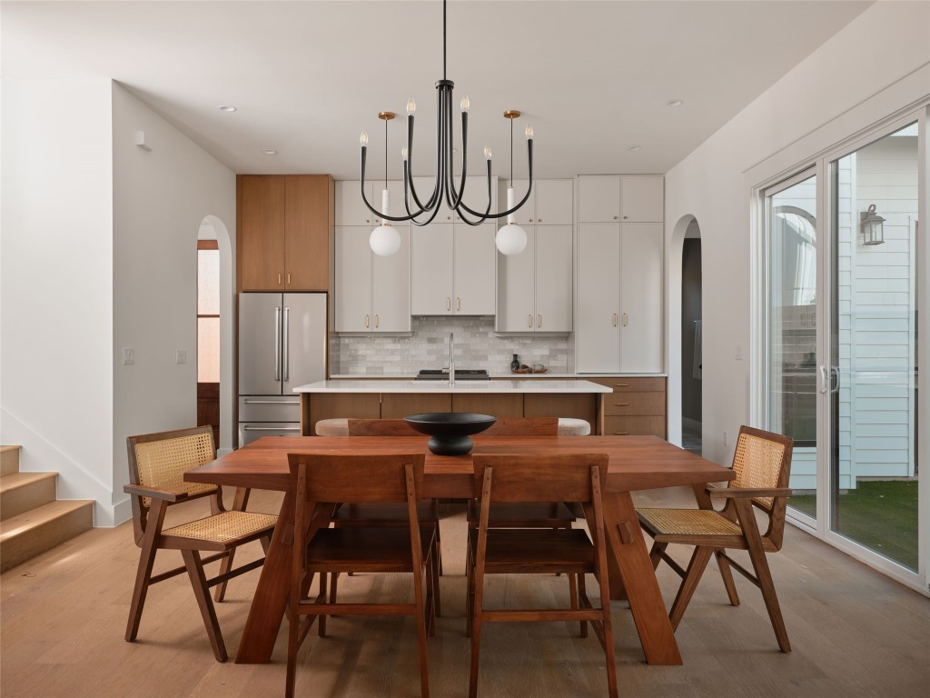 610 Allen Street, Unit 1 Austin, TX 78702 - Photo 6 of 32 Dining area featuring arched walkways, a chandelier, light wood-style flooring, and stairs