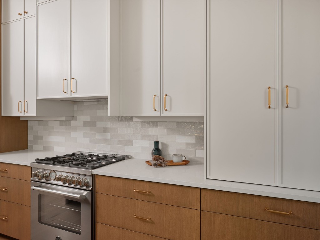 610 Allen Street, Unit 1 Austin, TX 78702 - Photo 9 of 32 Kitchen with stainless steel stove, white cabinets, tasteful backsplash, and light stone countertops