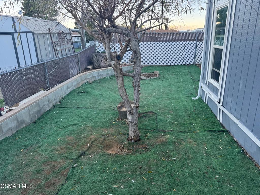 40701 Rancho Vista Boulevard, Unit 76 Palmdale, CA 93551 - Photo 19 of 31 a view of a backyard with wooden fence and a large tree