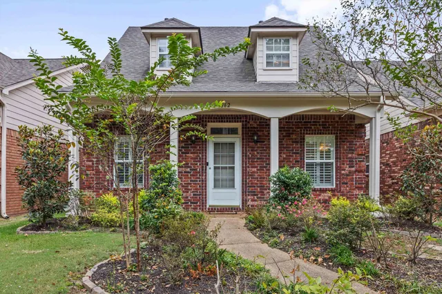 front view of a house with potted plants and a yard