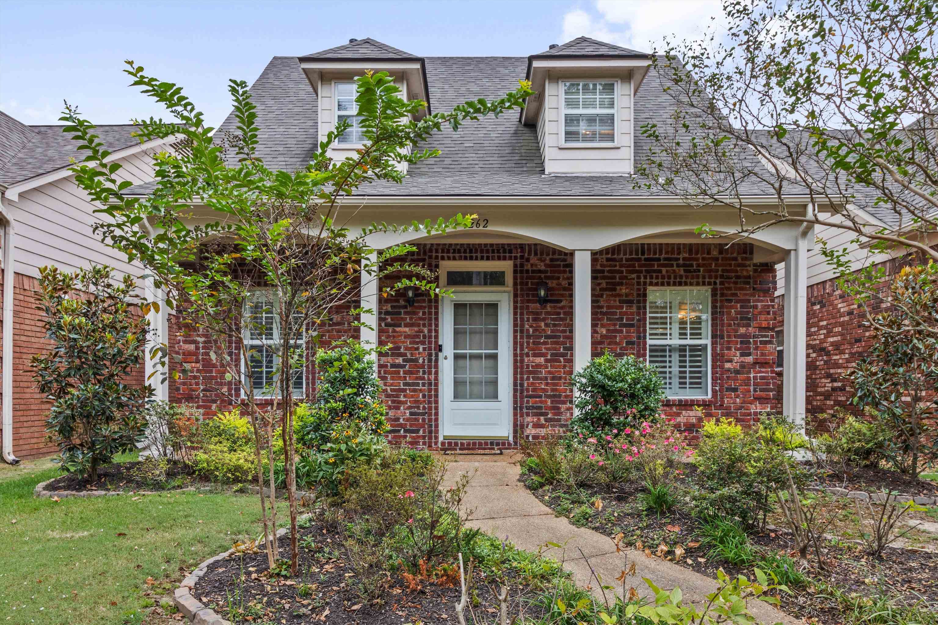 front view of a house with potted plants and a yard