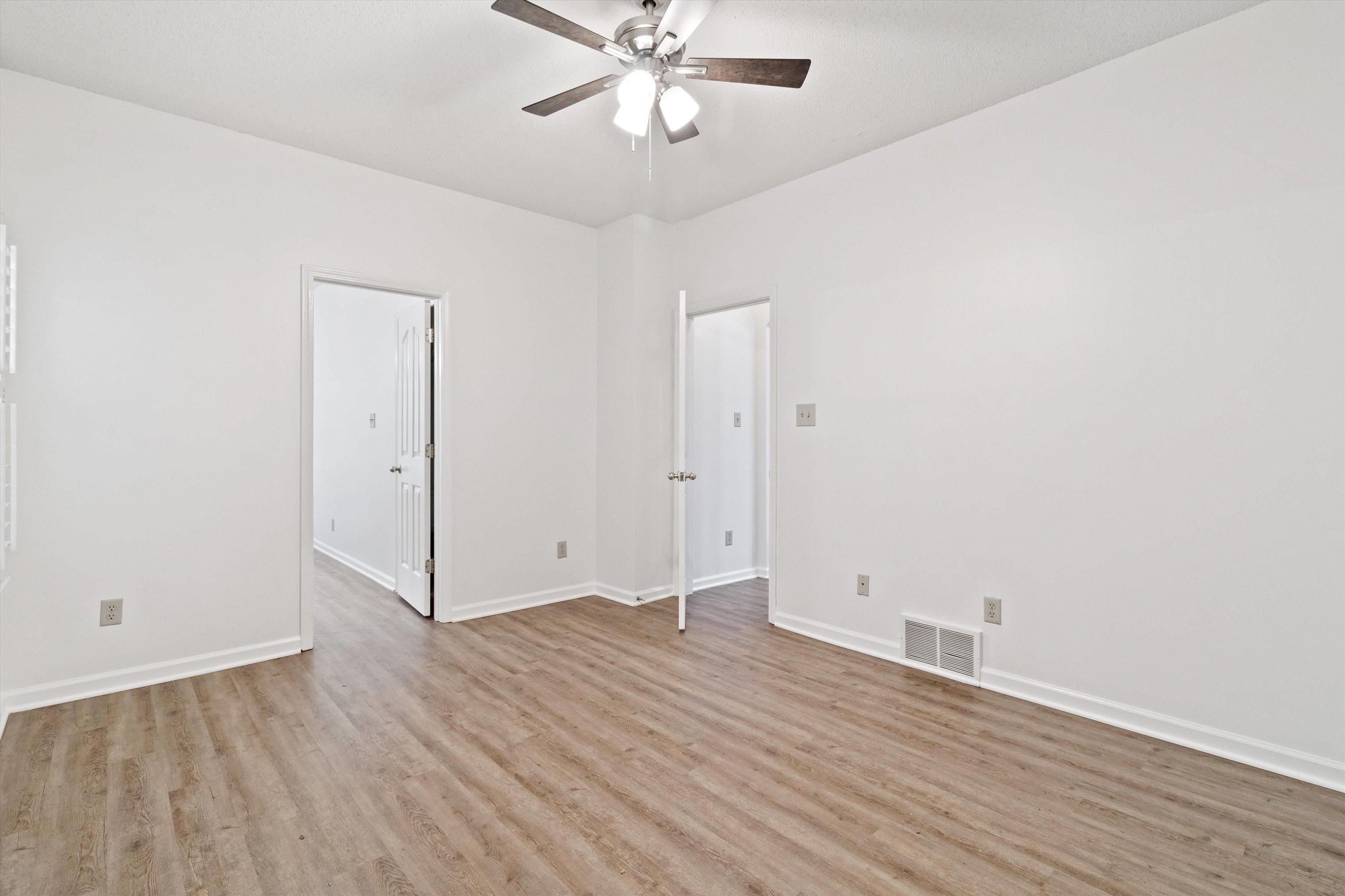 1262 South Collierville Arlington Road Collierville, TN 38017 - Photo 16 of 26 an empty room with wooden floor and fan