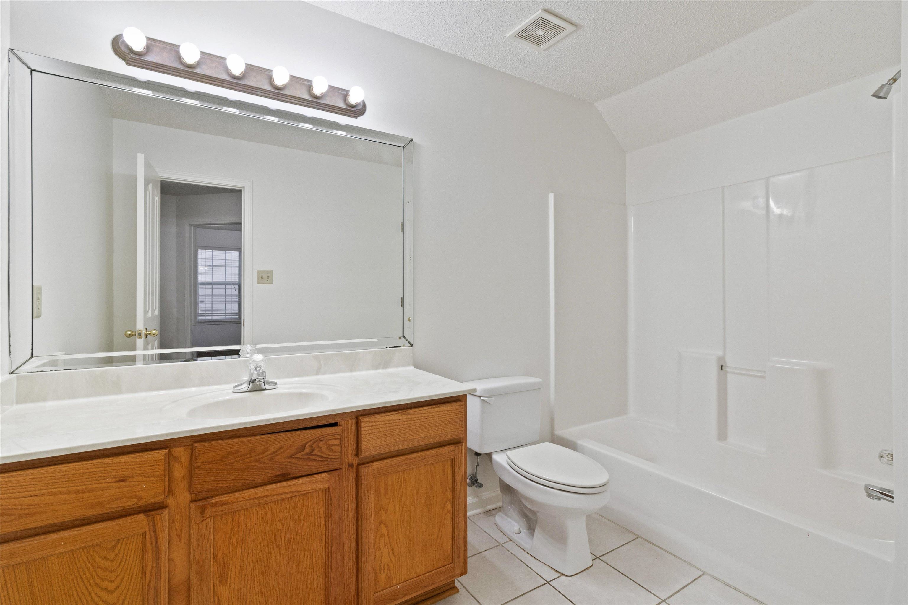 1262 South Collierville Arlington Road Collierville, TN 38017 - Photo 23 of 26 a bathroom with a toilet a sink a mirror and a bathtub