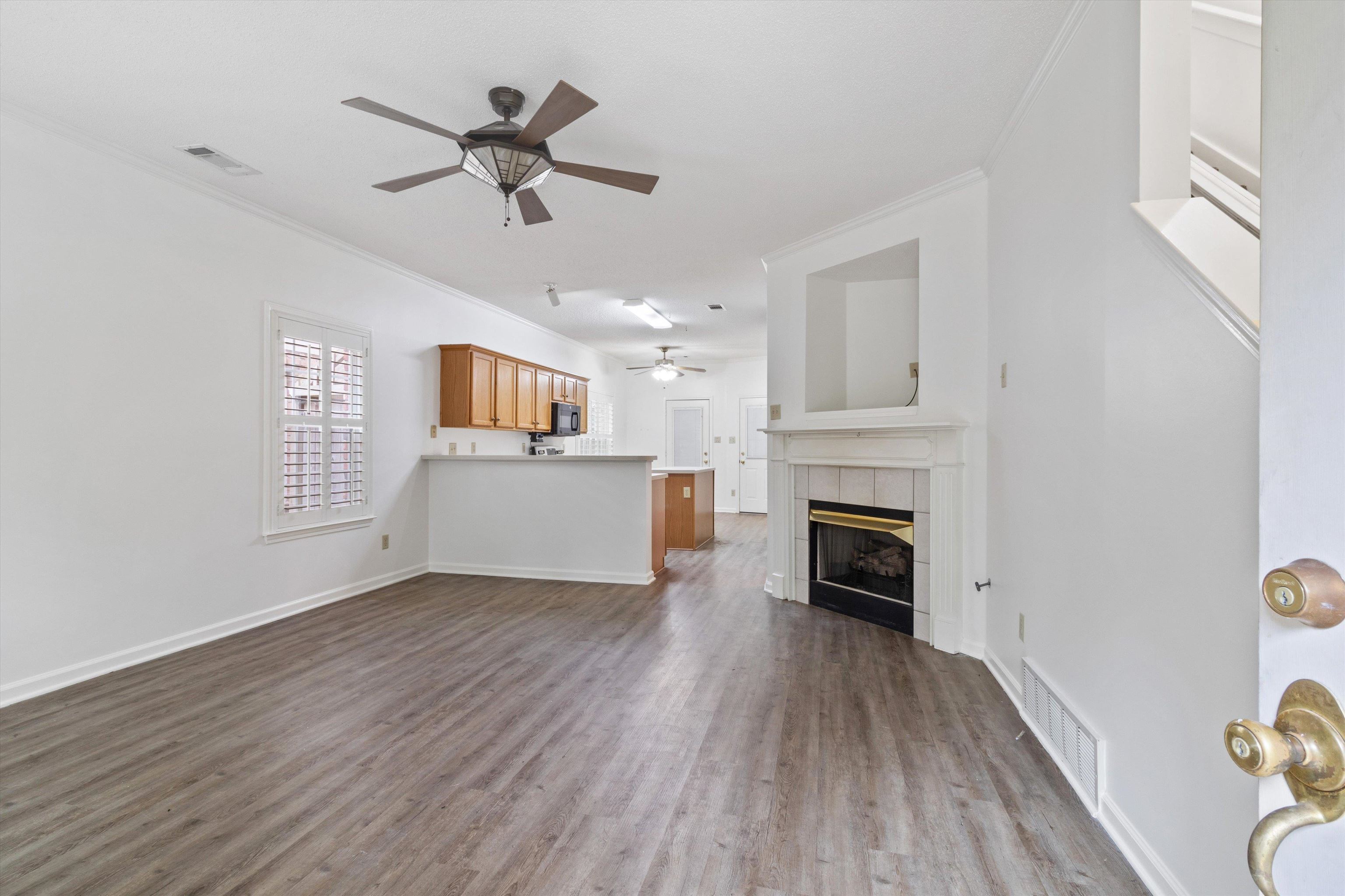 1262 South Collierville Arlington Road Collierville, TN 38017 - Photo 6 of 26 an empty room with fireplace wooden floor chandelier fan and windows