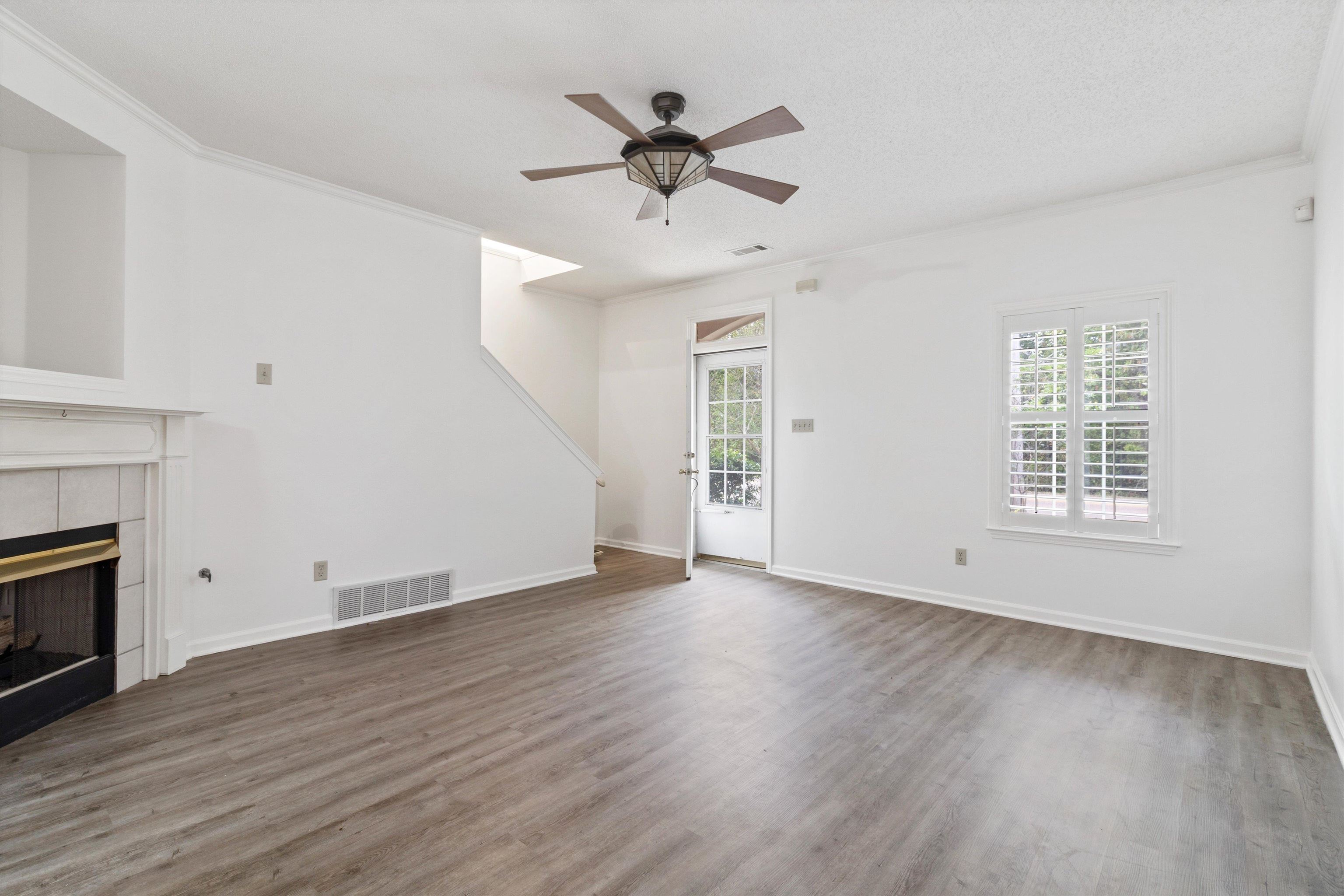 1262 South Collierville Arlington Road Collierville, TN 38017 - Photo 7 of 26 an empty room with wooden floor a ceiling fan and windows