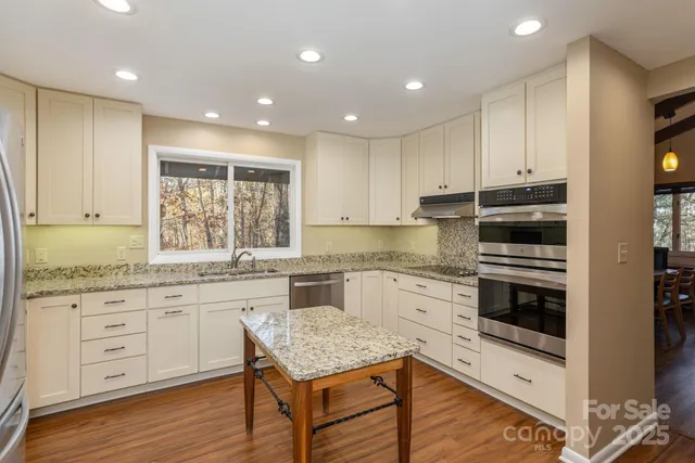 a kitchen with granite countertop cabinets stainless steel appliances and a counter space