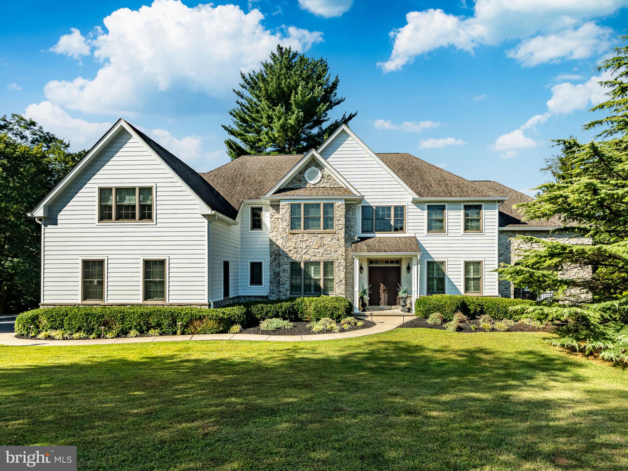 a front view of a house with a garden and trees