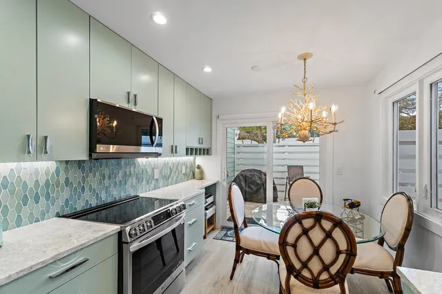 a kitchen with stainless steel appliances granite countertop a kitchen island a stove a dining table and chairs