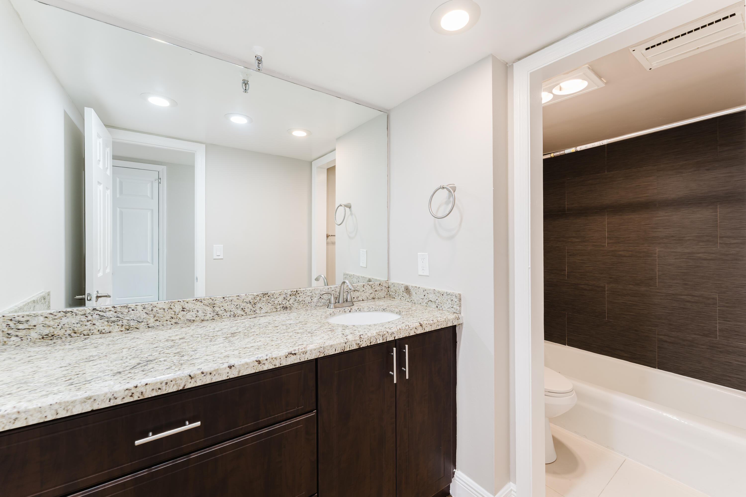 859 Jeffery Street, Unit 208 Boca Raton, FL 33487 - Photo 25 of 39 a bathroom with a granite countertop sink a large mirror and a bathtub
