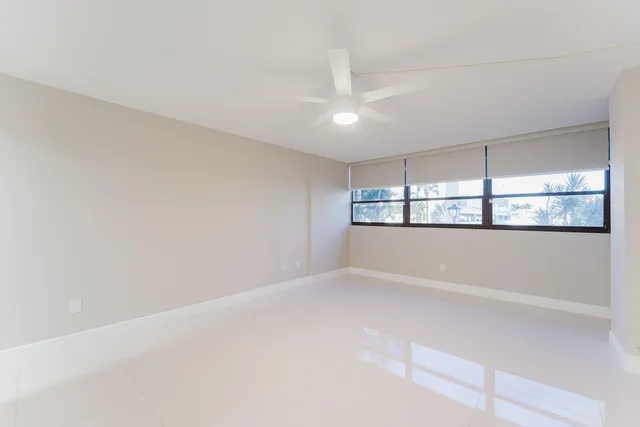 an empty room with a windows and ceiling fan