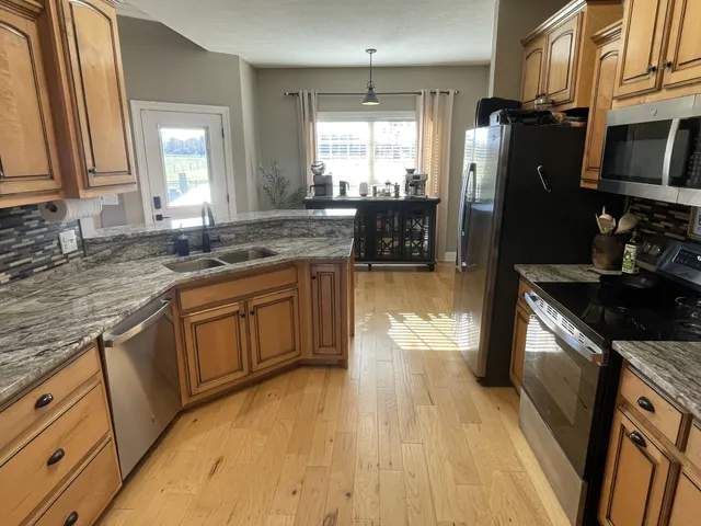 a kitchen with stainless steel appliances granite countertop a stove a sink a refrigerator and dishwasher