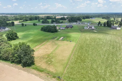 a view of a lake with lawn chairs and large trees