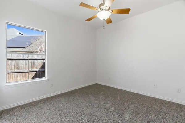 an empty room with a window and a fan